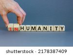 Small photo of Humanity or inhumanity symbol. Businessman turns wooden cubes changes the word inhumanity to humanity. Beautiful grey table grey background, copy space. Business, humanity or inhumanity concept.