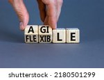 Small photo of Flexible and agile symbol. Concept words Flexible and agile on wooden cubes. Businessman hand. Beautiful grey table grey background. Business flexible and agile concept. Copy space.