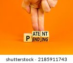 Small photo of Patent pending symbol. Concept words Patent pending on wooden cubes. Businessman hand. Beautiful orange table orange background. Business and patent pending concept. Copy space.