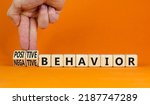 Small photo of Positive or negative behavior symbol. Businessman turns cubes, changes words negative behavior to positive behavior. Orange background, copy space. Psychology, positive or negative behavior concept.