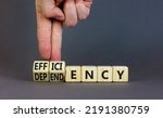 Small photo of Efficiency or dependency symbol. Businessman turns cubes, changes the word dependency to efficiency. Beautiful grey table, grey background, copy space. Business, efficiency or dependency concept.