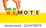 Small photo of Promote or demote symbol. Businessman turns cubes and changes the word 'demote' to 'promote'. Beautiful yellow table, white background. Business, demote or promote concept. Copy space.