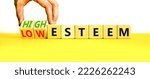 Small photo of High or low esteem symbol. Concept words High esteem and Low esteem on wooden cubes. Businessman hand. Beautiful yellow table white background. Business high or low esteem concept. Copy space.