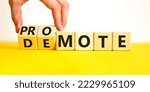 Small photo of Promote or demote symbol. Businessman turns cubes and changes the word 'demote' to 'promote'. Beautiful yellow table, white background. Business, demote or promote concept. Copy space.