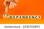Small photo of Codependency or dependency symbol. Concept words Codependency and dependency on wooden cubes. Psychologist hand. Beautiful orange background. Psychological codependency dependency concept. Copy space.