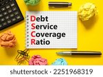 Small photo of DSCR debt service coverage ratio symbol. Concept words DSCR debt service coverage ratio on white note on beautiful yellow background. Business DSCR debt service coverage ratio concept. Copy space.