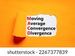 Small photo of MACD symbol. Concept words MACD moving average convergence divergence on white paper on beautiful orange background. Business MACD moving average convergence divergence concept. Copy space.