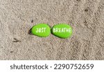 Small photo of Just breathe and psychological symbol. Concept words Just breathe on beautiful green stone. Beautiful sand sea beach background. Business psychological and Just breathe concept. Copy space.