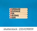 Small photo of ARPPU average revenue per paying user symbol. Concept words ARPPU average revenue per paying user on wooden stick. Beautiful blue background. Business ARPPU average revenue per paying user concept.