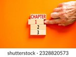 Small photo of Time to chapter 1 symbol. Concept word Chapter 1 2 3 on wooden block. Businessman hand. Beautiful orange table orange background. Business planning and time to chapter 1 concept. Copy space.