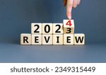 Small photo of 2024 review new year symbol. Businessman turns a wooden cube and changes words Review 2023 to Review 2024. Beautiful grey background, copy space. Business 2024 review new year concept.