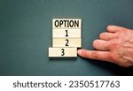 Small photo of Time to option 3 symbol. Concept word Option 1 2 3 on wooden block. Businessman hand. Beautiful grey table grey background. Business planning and time to option 3 concept. Copy space.