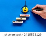 Small photo of Anything is possible symbol. Concept words Anything is possible on beautiful wooden blocks. Beautiful blue table blue background. Businessman hand. Business anything possible concept. Copy space.
