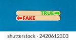 Small photo of True or fake symbol. Concept word True or Fake on beautiful wooden stick. Beautiful blue table blue background. Business and true or fake concept. Copy space.
