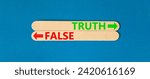 Small photo of Truth or false symbol. Concept word Truth or False on beautiful wooden stick. Beautiful blue table blue background. Business and truth or false concept. Copy space.