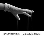 Small photo of Hand in medical glove with strings on fingers. Fraud, manipulation in medicine, conspiracy theory concept. Black and white. High quality photo
