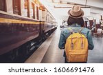 Young asian woman traveler with backpack in the railway, Backpack and hat at the train station with a traveler, Travel concept. Woman traveler tourist walking at train station