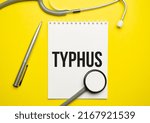 Small photo of The word typhus written on a white notepad on a yellow background