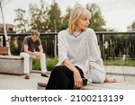 Small photo of Mature couple in a bad mental condition after a quarrel outdoors. Adult couple man and woman trying to overcome anxiety and disorder after a break-up scene.