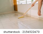 Small photo of Man wiping floor with the mop. Janitor washing the dirty floors. Guy mopping the balcony on a sunny day. Person doing home chores. Young fellow using cleaning equipment to dust the surface.