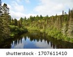 Peshekee River in Upper Peninsula of Michigan with reflection of forest and sky.