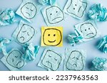 Small photo of A sad face watching smiling faces from afar. Happy and sad faces drawn on blue stickers. Concepts of exclusion, difference, jealousy. High quality photo