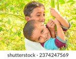 Small photo of A baby boy and a girl trying to climb on a tree. Moving towards sauces concept of climbing on tree. Learning climbing process. Pakistani kid practicing to climb on a tree. Asian kid climbing on tree.