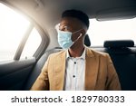 Young Man Wearing Mask In Back Of Taxi During Health Pandemic Going Out On Date