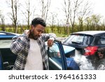 Small photo of Uninsured male driver rubbing neck in pain from whiplash injury standing by damaged car after traffic accident for which he is to blame