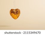 Levitating heart made of sequins. A heart made of copper sequins develops on a beige background.
