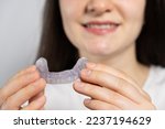 Small photo of A woman holds dental mouthguard, splint for the treatment of dysfunction of the temporomandibular joints, bruxism, malocclusion, to relax the muscles of the jaw.