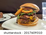 Small photo of Wild burger with three layers of meat, three of melted cheddar cheese, lots of bacon, onion rings, lots of bbq sauce, and some arugula leaves to bear witness.