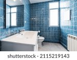 Small photo of Bathroom with gloss white lacquered wooden cabinet with white resin basin, frameless rectangular mirror and walls tiled with kitsch blue tile