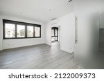 Small photo of Empty living room in a loft with large black aluminum windows with gray wood-like ceramic floors and opaque glass sliding door