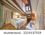 Bedroom of an old house located in the attic with sloping ceilings with oak floors and exposed wooden beams
