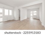 Small photo of Empty living room with laminated flooring and recently finished smooth white walls with access to two similar terraces