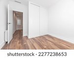 Small photo of bedroom with wooden floors and white baseboards, doors and fitted wardrobes with sliding doors and aluminum radiator behind the door