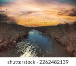 Small photo of an aerial shot of the flowing waters of the river at Lower Pool West at Lake Lanier with bare winter trees and powerful clouds at sunset in Cummings Georgia USA