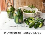 Small photo of Preparation of canned cucumbers or fermented cucumbers in glass jars. Ingredients for pickling cucumbers. Cucumbers, dill, garlic. Glass jars with pickles. Processing of the autumn harvest.