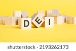 Small photo of wooden blocks with text DEI on yellow background. dei - short for diversity equity inclusion