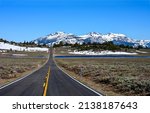 The road through the valley to the snow capped mountains. Mountain valley road landscape. Snowy mountain valley road way