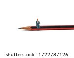 A businessman using a laptop sits on a pencil - Tiny People Working From Home