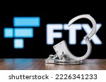 Small photo of Kazan, Russia - Nov 14, 2022: FTX is cryptocurrency exchange. Open handcuffs on table against background of FTX logo. The concept of trial. Сoncept of investigation.