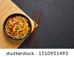 Vegetarian Schezwan Noodles or Vegetable Hakka Noodles or Chow Mein in black bowl at dark background. Indo-chinese cuisine hot dish with udon noodles, vegetables and chilli sauce. Copy space