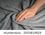 Woman touching grey blanket, close up. Close up of hand touching soft blanket. Gentle and fluffy blanket between fingers.