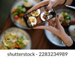 Top view woman taking photo of food with phone in hand. Food photography with phone. Social media photography.