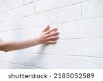 Woman's hand on the background of a white brick wall. A woman touches the old wall of the monastery.