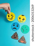 Small photo of top view arrangement with different emotions. day of a smile, a face with emotions made of paper, shows the mood of a turd on your hand