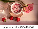 Small photo of Milk with strawberry slices. In soup tureen. Pink wooden background. Top view, flat lay. Strawberries. Pink tulip. Pink marshmallows