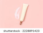 Small photo of Mockup of face and eye cream squeeze cosmetic tube with long nozzle and bronze screw cap and big smear of moisturizer on pink background. Natural organic spa cosmetics concept, flat lay, top view.